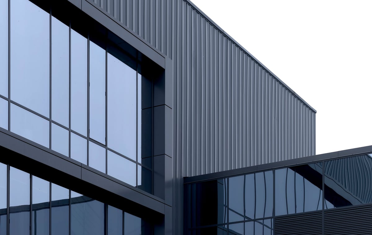 Fachada de nave industrial moderna con paneles de vidrio y recubrimiento metálico oscuro